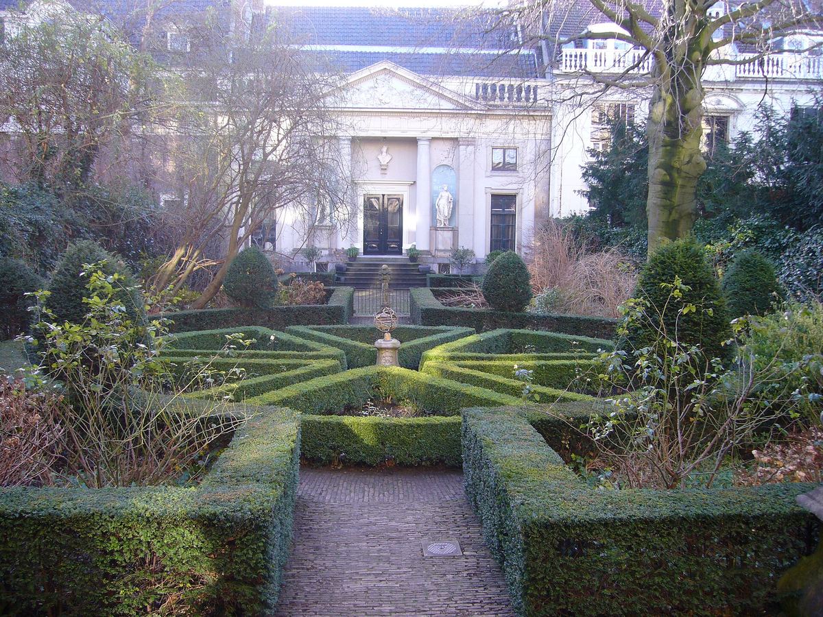 El jardín formal del Museo Van Loon con setos de boj y la casa del cochero
