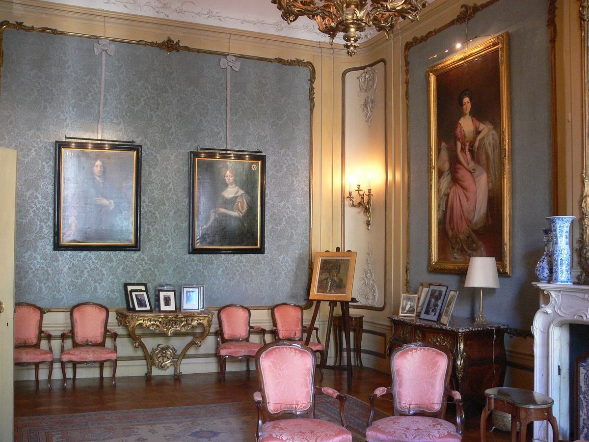 Un salón en el Museo Van Loon con retratos familiares y sillas rosas